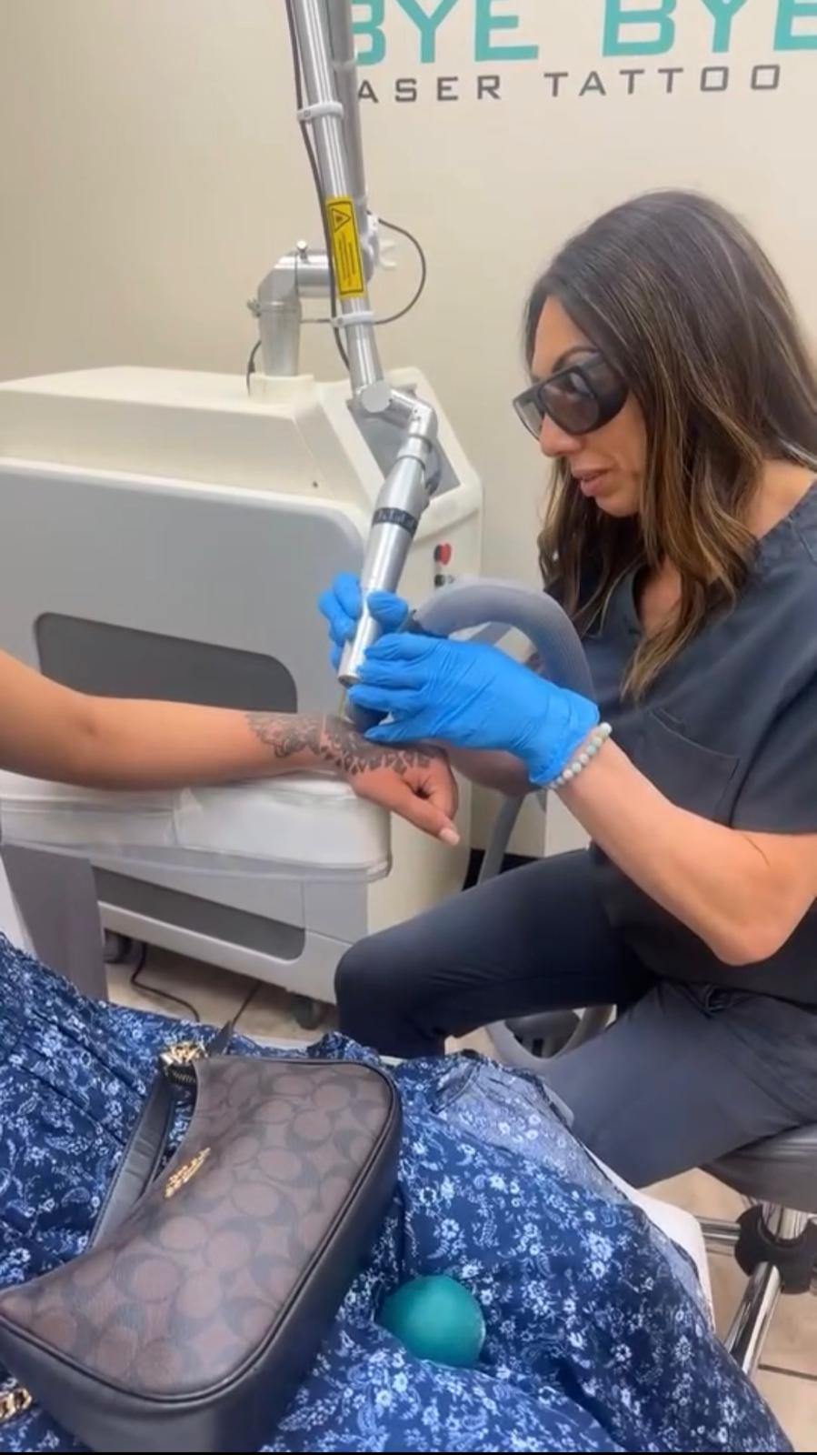 Laser tattoo removal treatment at Bye Bye Ink NYC, technician in protective eyewear treating a tattoo on a client's hand